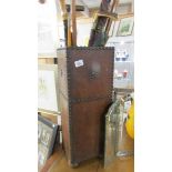 A leather covered stick stand with walking sticks and umbrella.