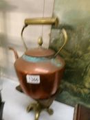 A copper kettle on a brass trivet,