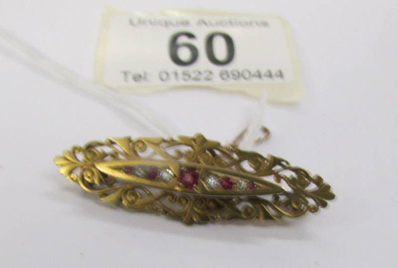 An antique ruby and diamond brooch in 15 carat hall marked gold with attached safety chain. - Image 2 of 3