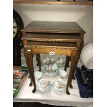 An Edwardian. nest of tables with figured walnut tops under glass.