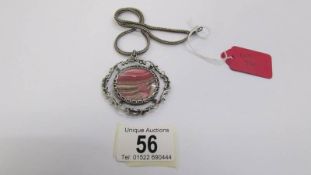 A fancy silver open work pendant with attached silver chain and set with pink/grey banded agate,