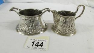 A heavily embossed continental silver cream jug and sugar bowl, marked 800.