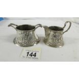 A heavily embossed continental silver cream jug and sugar bowl, marked 800.