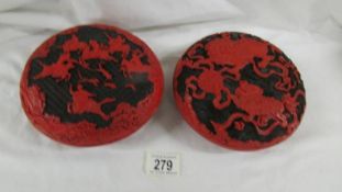 A pair of black and red cinnabar lacquer circular lidded boxes, one decorated with guardian lions,