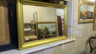 A large gilt framed bevel edged mirror.