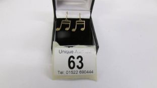 A pair of 9ct gold pendant earrings as music scores with silver shepherd hook fittings.