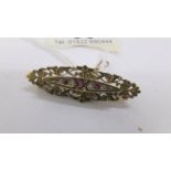 An antique ruby and diamond brooch in 15 carat hall marked gold with attached safety chain.
