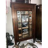 An Edwardian oak cabinet with bevelled mirror panels painted with milinary, Chicago advertising.