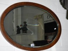 A mid 20th century oval oak framed bevel edged mirror.