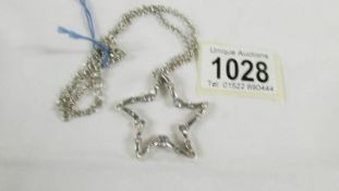 A stone set star designed pendant in silver with attached silver chain.