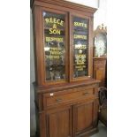 A glazed top cabinet with Reece & Son., lettering.