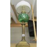 A brass oil lamp with green glass shade.