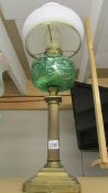 A brass oil lamp with green glass shade.