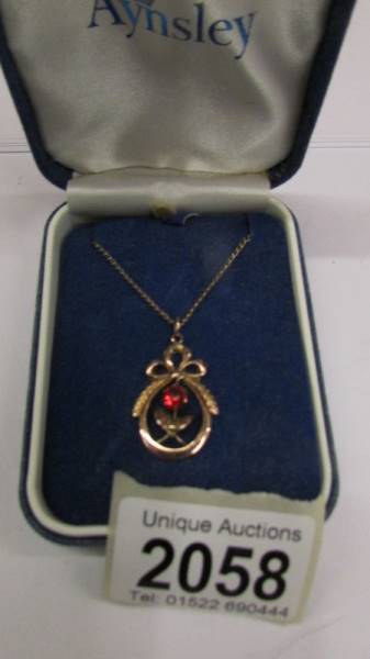 An early 20th century rose gold pendant surmounted with a ribbon stone set,