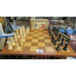 A chess board and chess set, missing black queen.