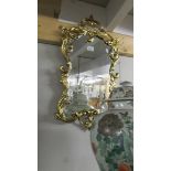 A shield shaped mirror in gold coloured frame. 93 cm tall.