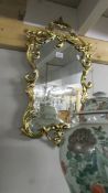 A shield shaped mirror in gold coloured frame. 93 cm tall.