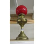 A brass oil lamp with red shade.