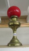 A brass oil lamp with red shade.