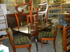 A mahogany drop lead table on brass lion paw casters with 6 green dralon deep buttoned chairs.