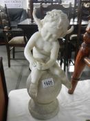 A resin garden ornament of a winged cherub sitting on an orb.