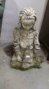 An old garden figure of a seated girl.