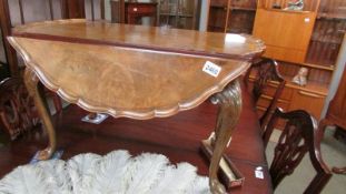 A lovely walnut table with drop sides, pie crust edge and on pad feet.