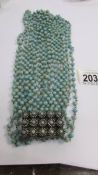 An unusual 11 strand bead necklace in a turquoise colour with a flower filled clasp in the style of