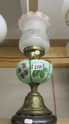 A brass oil lamp with hand painted glass font and later shade.