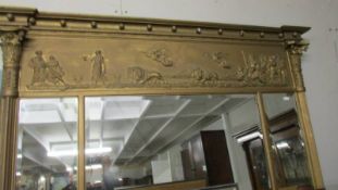 A gilded bevel edged overmantel mirror with top figural frieze.