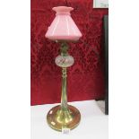 An arts and crafts oil lamp on brass base with glass font and pink glass shade (no chimney).