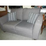 A grey fabric 2 seater sofa with 2 matching cushions