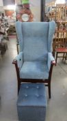 A high backed wing arm chair with stool.