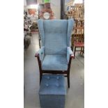 A high backed wing arm chair with stool.
