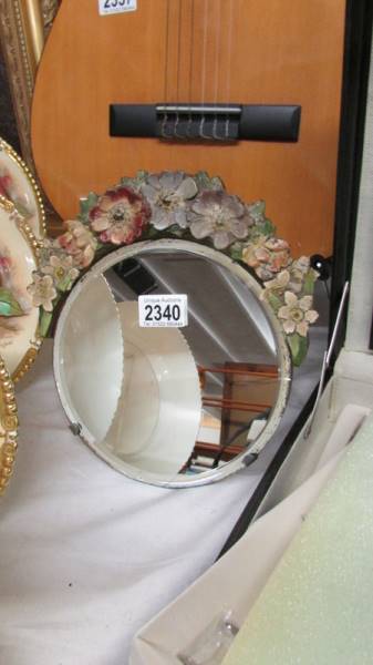 An antique oval mirror with painted floral decoration to top.