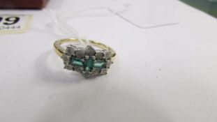 A yellow gold ring set with three oblong emeralds surrounded by diamonds. Size N.