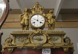 A gilded mantel clock surmounted figures.