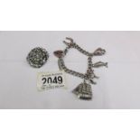 A vintage silver charm bracelet dated Birmingham 1976 together with a white stone brooch circa