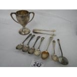 7 silver teaspoons, a pair of hall marked silver sugar nips and a silver trophy, 167 grams.