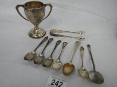 7 silver teaspoons, a pair of hall marked silver sugar nips and a silver trophy, 167 grams.