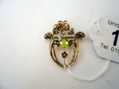 An ealry 20th century peridot and pearl brooch/pendant in gold.