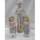 A pair of bisque porcelain figures of a boy and girl (19cm) and another bisque porcelain figure (33