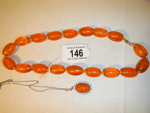 An amber necklace with 9ct gold clasp (approximately 50cm long) and and amber and enamel pendant in