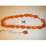 An amber necklace with 9ct gold clasp (approximately 50cm long) and and amber and enamel pendant in