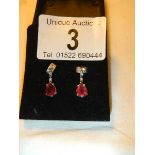 A pair of 14ct white gold earrings set with pear shaped rubies.