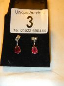 A pair of 14ct white gold earrings set with pear shaped rubies.