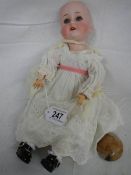 A bisque porcelain headed doll, missing wig but otherwise in good condition.