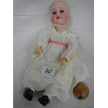 A bisque porcelain headed doll, missing wig but otherwise in good condition.