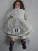 An early 20th century German porcelain doll by Shoenau & Hoffmeister with moveable joints,