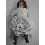 An early 20th century German porcelain doll by Shoenau & Hoffmeister with moveable joints,